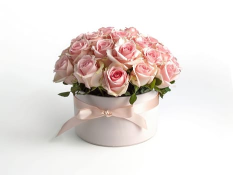 The delicate bouquet showcases vibrant pale pink roses surrounded by lush green leaves, elegantly placed in a soft pink container on a weathered wooden surface.