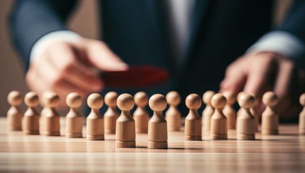Businessman hands arranging wooden figures, concept of leadership, teamwork, and human resources management.
