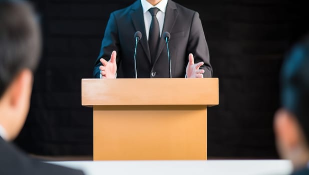 Businessman giving speech at podium with microphones during conference. Concept of public speaking, leadership, and business presentation.