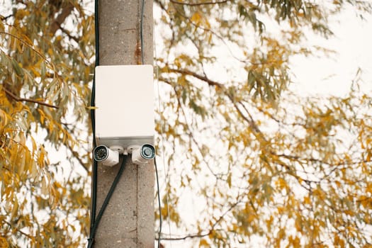A utility pole equipped with various telecommunication devices stands tall amidst the vibrant autumn foliage