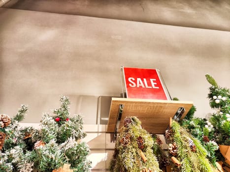 Shoppers view a sale sign above decorated artificial Christmas trees in a retail store during the winter holiday shopping season.