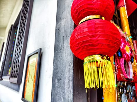 Decorative red lanterns hang from a building, symbolizing good luck and joy during a festive celebration in the area.