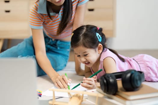 A joyful moment of a mother and daughter bonding while drawing together on the floor in a cozy home setting.