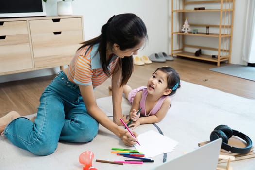 A joyful mother and daughter bonding over coloring activities on the floor of a cozy, modern living room.