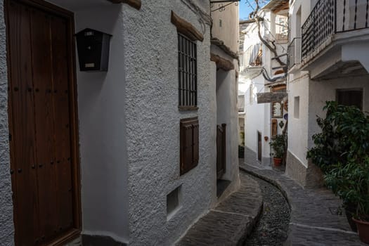 Rustic narrow alley with white buildings featuring wooden doors and window shutters on a sunny day, Alpujarras, granada, andalucia, espa a,