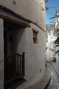 White narrow alley with wooden railings and rustic architecture under a bright sunny sky, Alpujarras, granada, andalucia, espa a,