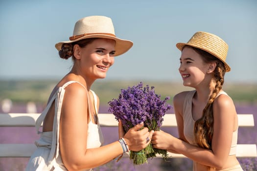 A woman and a child are sitting on a bench in a field of purple flowers lavande. The woman is holding a bouquet of flowers and the child is holding a bouquet of flowers as well.
