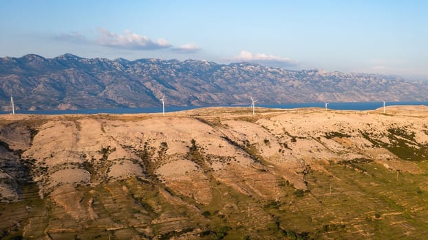 Modern wind turbines generate energy on hill on Pag Island on sunny day. Sustainable source of power reduces reliance on fossil fuels in Croatia