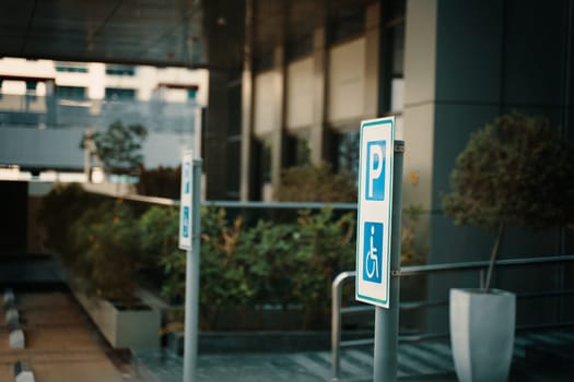 A parking sign with the letter P indicates parking available for building visitors. The facade of the building features glass windows and wooden doors