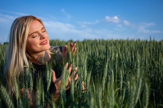 On a sunny day, a young and attractive female farmer stands in her wheat field, overseeing her bountiful crops. Dressed in practical work attire, her blonde hair catching the sunlight, she exudes a sense of vitality and dedication. With a warm smile revealing her pearly white teeth, she radiates contentment and satisfaction. The wheat stalks tower around her, almost reaching her height, their vibrant green hue a striking contrast against the blue sky. As she surveys the golden expanse before her, her satisfaction with the abundant harvest is evident. Against the backdrop of the sunlit landscape, her presence adds a touch of rural charm to the scene. She looks at her crops with happiness. This captivating image captures the essence of agricultural life, where hard work and perseverance yield fruitful rewards, and the beauty of nature is celebrated with every successful harvest