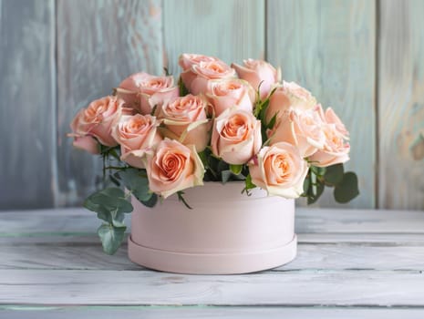 The delicate bouquet showcases vibrant pale pink roses surrounded by lush green leaves, elegantly placed in a soft pink container on a weathered wooden surface.