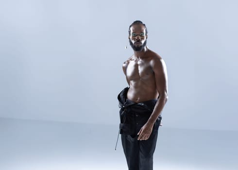 Confident shirtless African American gay man with bright makeup isolated on white background, Gay muscular macho man wearing make-up looking at camera.
