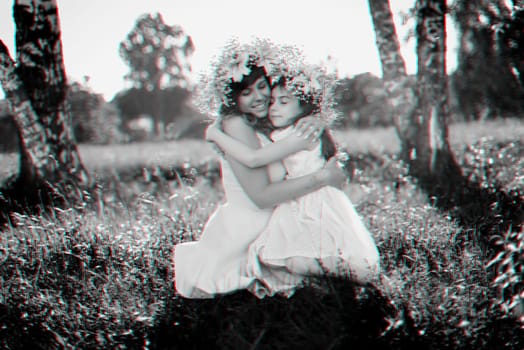 mom hugs her daughter sitting on the grass outdoors on a Sunny summer day. Black and white monochrome photography with 3D glitch effect