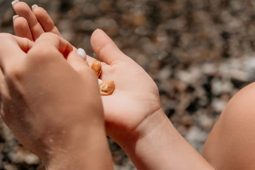Woman eating milky almond nuts. A young caucasian woman choping fresh green almond after morning fitness yoga near sea. Only hands are visibly. Healthy vegan food. Slow motion. Close up