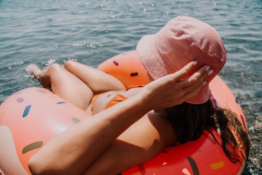 Summer Vacation Woman in hat floats on an inflatable donut mattress, a water toy swim ring. Unrecognizable young woman relaxing and enjoying family summer travel holidays vacation on the sea