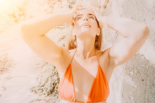 Woman travel sea. Young Happy woman in a long red dress posing on a beach near the sea on background of volcanic rocks, like in Iceland, sharing travel adventure journey