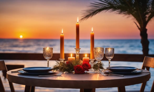 A round wooden table set for two with blue plates, silverware, and wine glasses. In the center are candles and red roses on a bed of green foliage