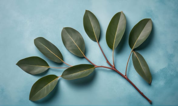 A branch with seven green leaves lays on a blue surface, the leaves are arranged in a slightly curved pattern.