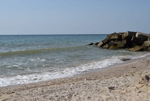 Rock fragments on a wild beach. The sky was clear and the waters of the sea beat on the rocks