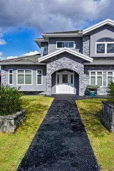 Nice residential house with stone texture walls and stone walls on front yard. Big family house with landscaped front yard