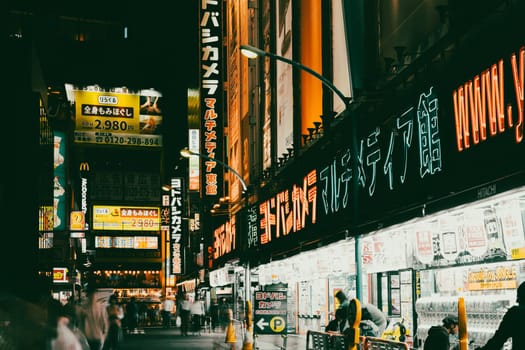 TOKYO, JAPAN - MAY 18 2019: Neon signs illuminate Tokyo’s busy Shinjuku neighborhood at night around Yodobashi camera store