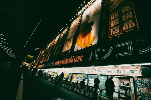 TOKYO, JAPAN - MAY 18 2019: Neon signs illuminate Tokyo’s busy Shinjuku neighborhood at night around Yodobashi camera store