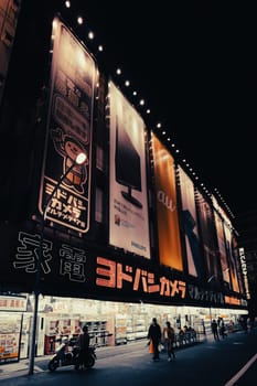 TOKYO, JAPAN - MAY 12 2019: Neon signs illuminate Tokyo’s busy Shinjuku neighborhood at night around Yodobashi camera store