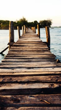 The wooden pier stretches out into calm waters under a warm sunset, surrounded by greenery, creating a peaceful atmosphere perfect for quiet contemplation or leisurely strolls - Generative AI