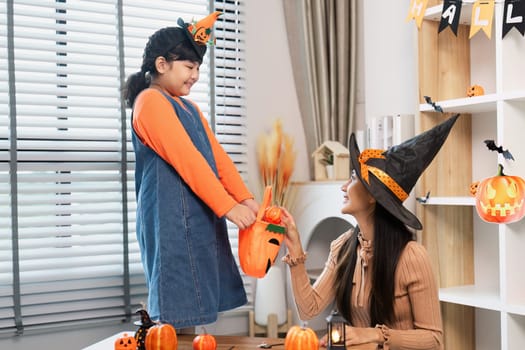 A mother and daughter enjoying Halloween festivities at home dressed in costumes and surrounded by festive decorations.