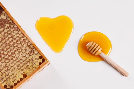 honey spoon with spilled honey in the shape of a heart and bee honeycomb on a white background top view, concept of love for the health of the body