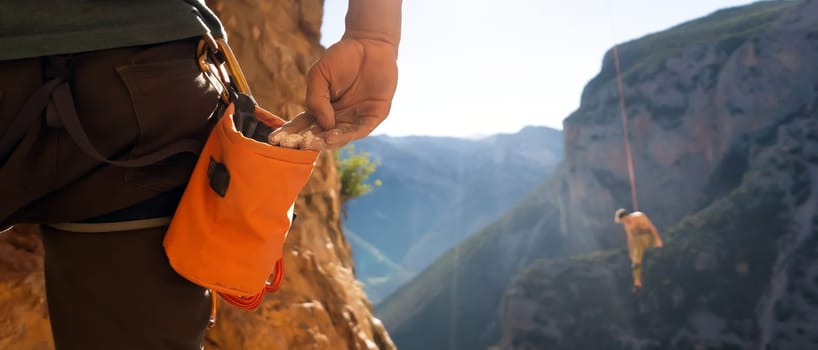 Male hand with magnesia powder close-up, against the background of beautiful mountains, the hand of climber who prepares for training outdoors, a man climbs in Twin Caves, Greece on a sunny day.