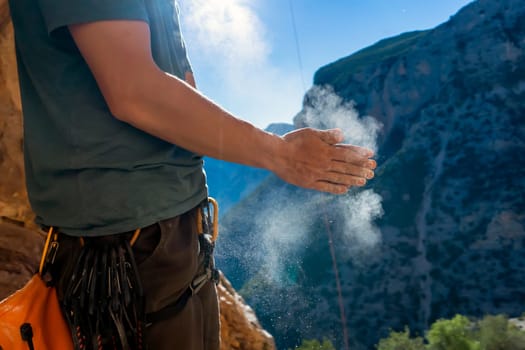 Male hands with magnesia powder close-up against the background of the mountains on a sunny day, the hands of a climber who prepares for outdoor training, a man is engaged in active sports in Greece.