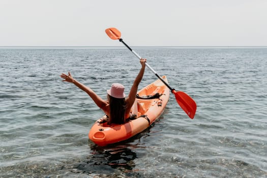 Happy smiling woman in kayak on ocean, paddling with wooden oar. Calm sea water and horizon in background