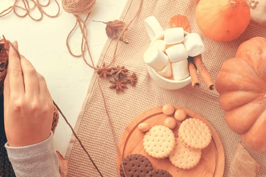 Cozy autumnal scene with knitting, assorted cookies, marshmallows, and pumpkins. Perfect for fall themes.