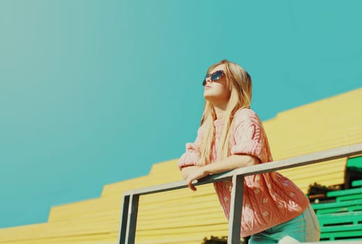 Portrait of young blonde woman in a city park on a sky background
