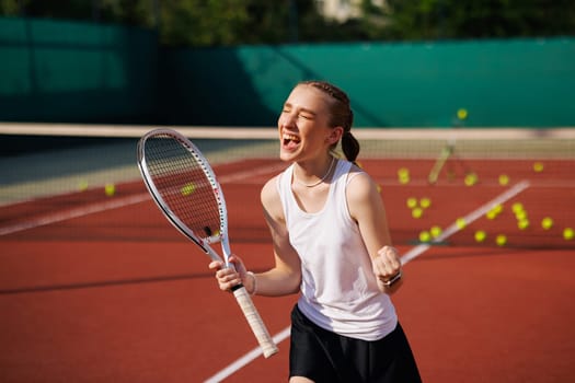 girl tennis player rejoices after scoring a goal, against the background of a tennis court, victory in a tennis tournament