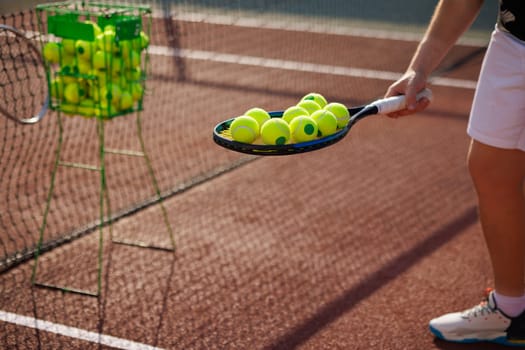 tennis player collecting balls on tennis court close up after training, tennis training concept