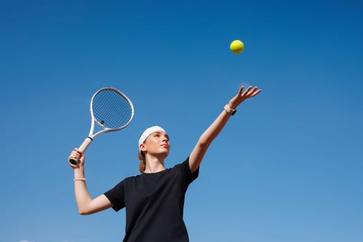 girl tennis player makes a hit with a tennis racket on a ball close-up on a sky background, concept of a tennis game