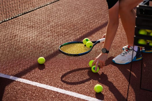 tennis player collecting balls on tennis court close up after training, tennis training concept