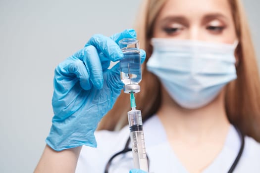 Health worker preparing vaccine, doctor drawing medicine into syringe close-up on white background, vaccine concept