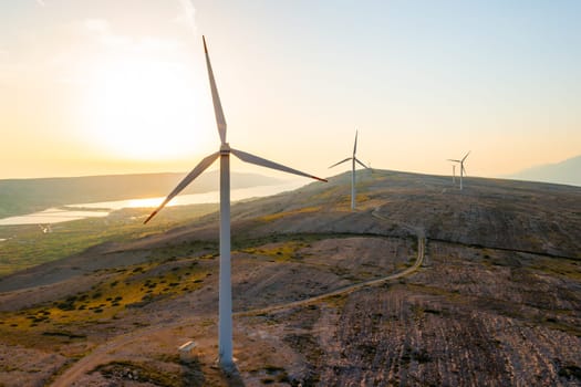 PAG ISLAND, CROATIA - JULY 14 2024: Large wind turbines mounted on hill of Pag Island at sunset. Innovation to transform wind into sustainable source of ecological electric power in Croatia