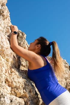 Close-up of a woman in a blue top and white leggings climbing a rocky surface, Latin woman, middle-aged, outdoors, climbing psicobloc in mallorca, balearic islands, spain,
