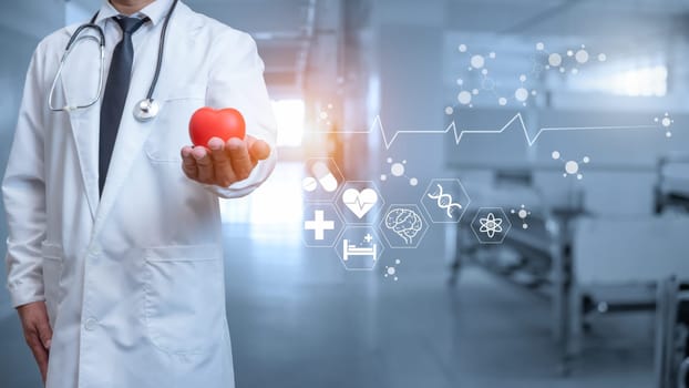 Doctor in lab coat holding red heart on hospital interior background