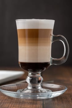 Multilayer coffee latte in glass cup on wooden table