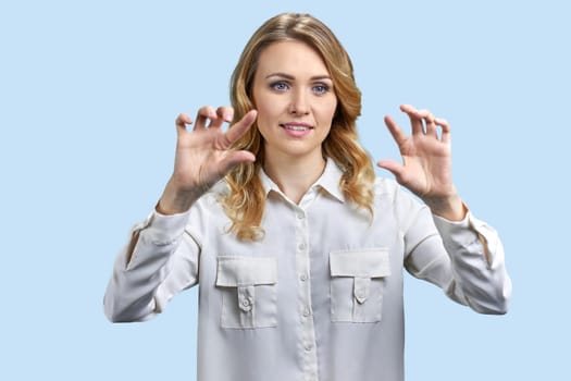 Portrait of businesswoman zooming in a tranparent virtual screen for copy space. Isolated on blue background.