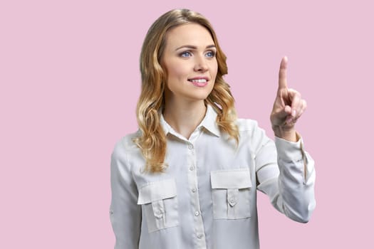 Business woman is touching an invisible virtual screen. Isolated on pink background.