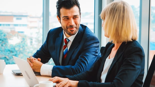 Two business people talk project strategy at office meeting room. Businessman discuss project planning with colleague at modern workplace while having conversation and advice on financial report. Jivy