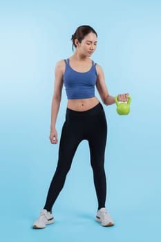 Vigorous energetic woman doing kettlebell weight lifting exercise on isolated background. Young athletic asian woman strength and endurance training session as body workout routine.