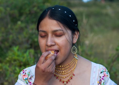 close-up of an indigenous girl with her eyes closed savoring a slice of orange in an orchard next to her house. Hispanic Heritage Month. High quality photo