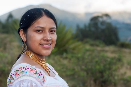 copy-space of beautiful young latin american girl looking at smiling camera with traditional indian dress and gold necklaces. Hispanic Heritage Month. High quality photo